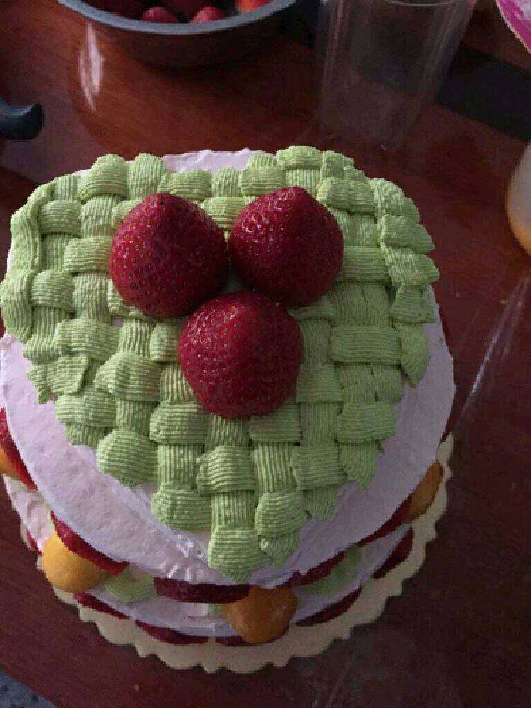 自制【三层生日蛋糕】,在抹上一层奶油开始裱花如图,摆上草莓。