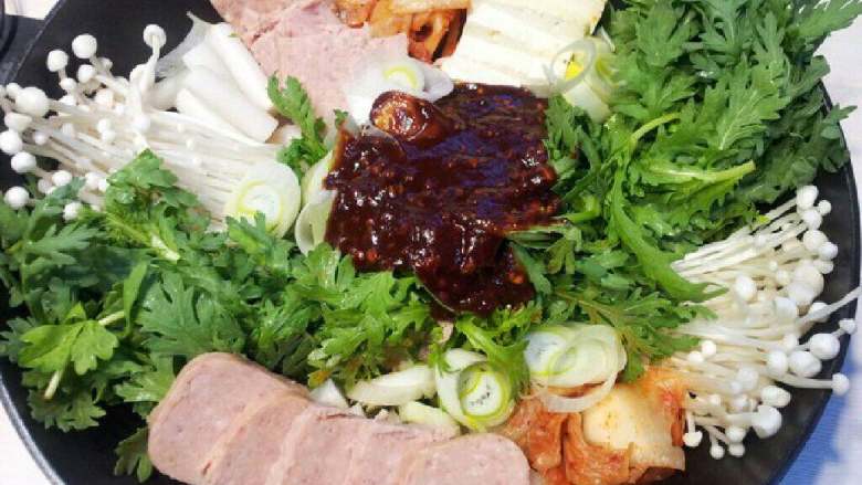 自制【部落火锅】,蒜末和调味料混合成调味酱,倒 入食材中央。