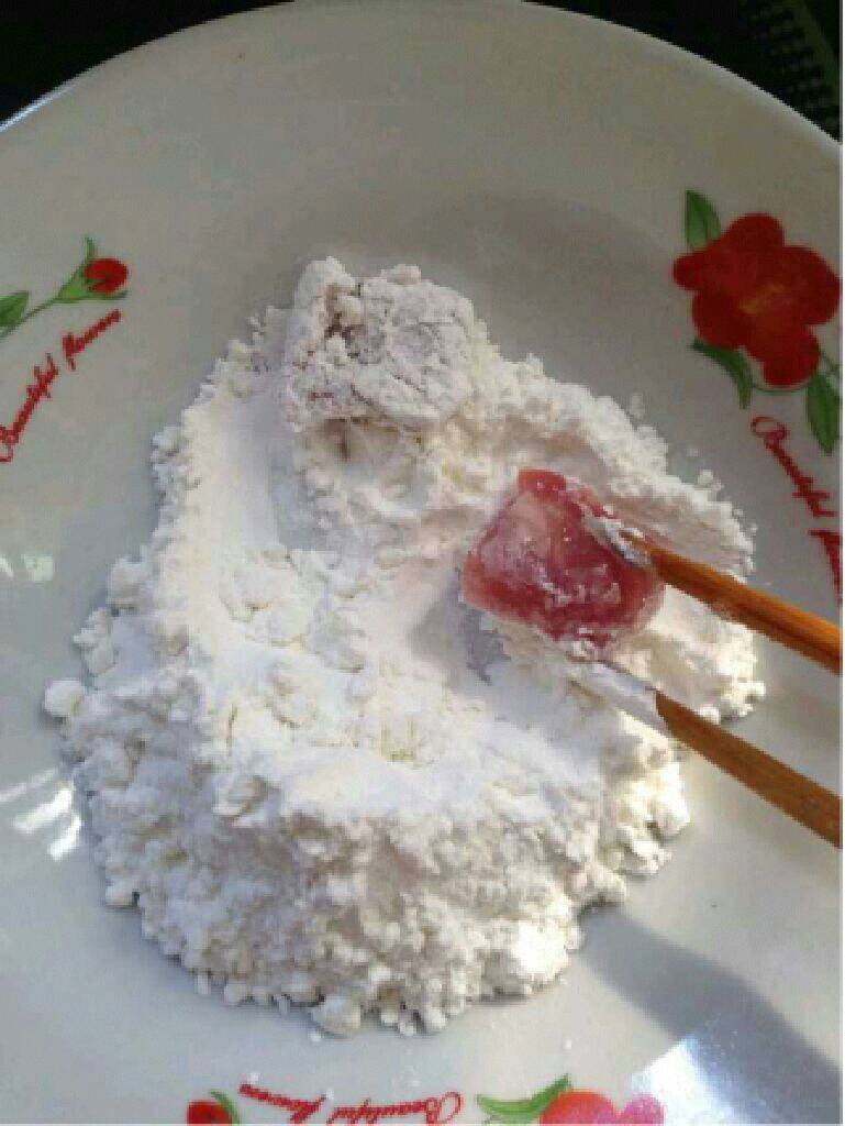 自制【菠萝咕噜肉】,盘子里到一些干淀粉,在把腌制好的肉放进裹满全身。
