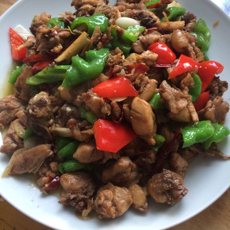 辣子鸡,如图加入青红椒块和蒜片,加入少许白糖,两三滴陈醋,一两滴香油,翻炒均匀出锅即可