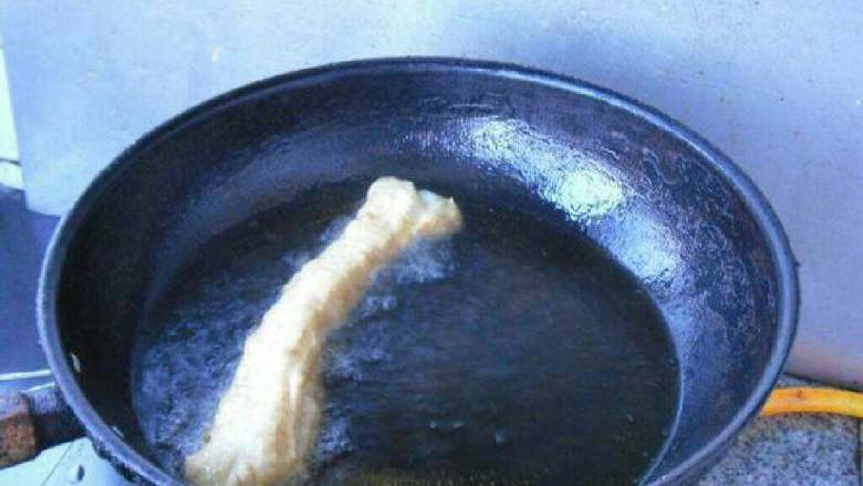 无矾健康油条,轻轻放入油锅炸制。用筷子翻动,炸至到金黄色即可。