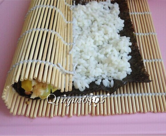 基础寿司,用寿司帘从自己这一端卷向另一端,边卷边一点点撤出帘子。
