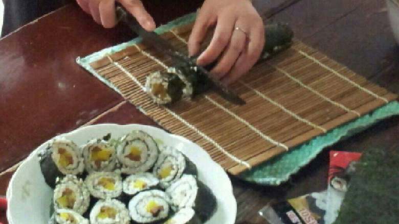 美味寿司卷,将卷成条的寿司条稍稍压一下紧,用刀切成小块。