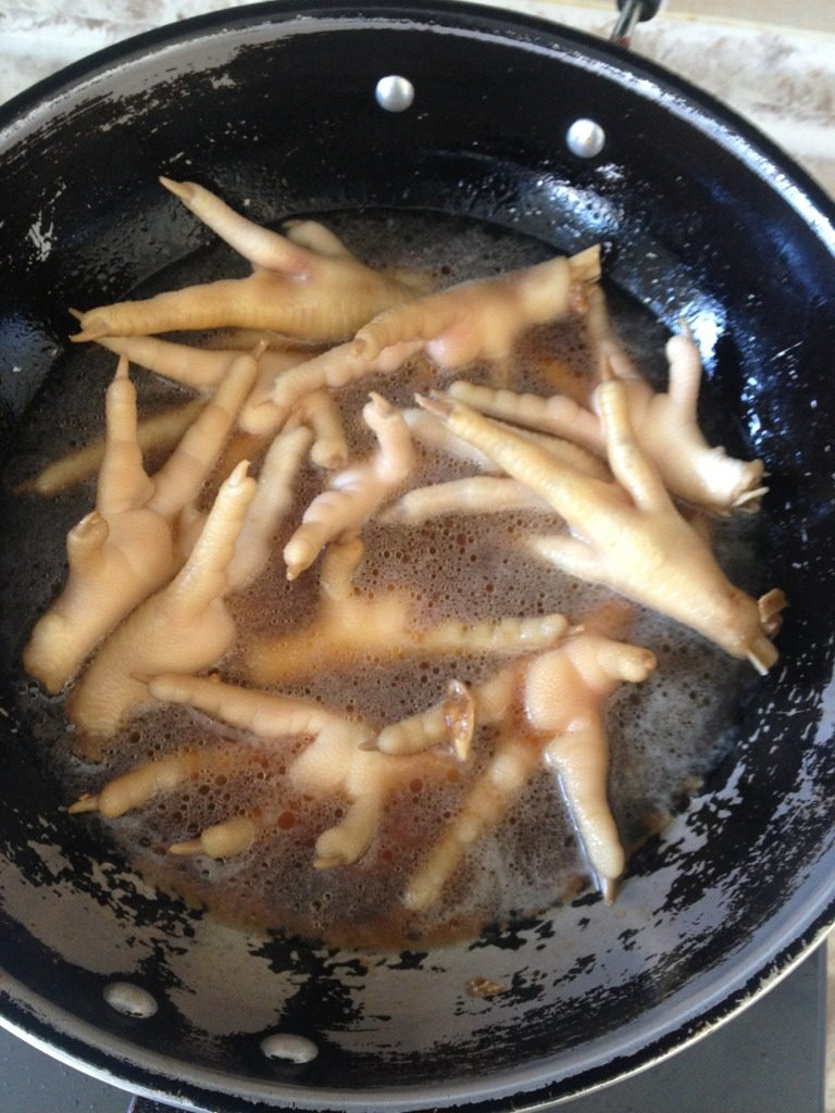 红烧鸡爪,如图，<a style='color:red;display:inline-block;' href='/shicai/ 2794'>大蒜</a>先入油锅，然后鸡爪，加白糖，酒，酱油翻炒出香味，加水沫过鸡爪，煮至收汁