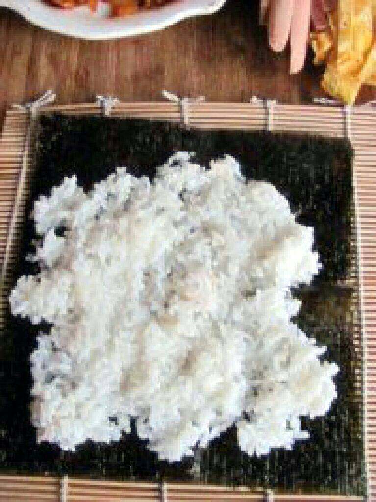 紫菜泡菜包饭,寿司卷帘上放海苔,然后把米饭均匀的铺在紫菜上。