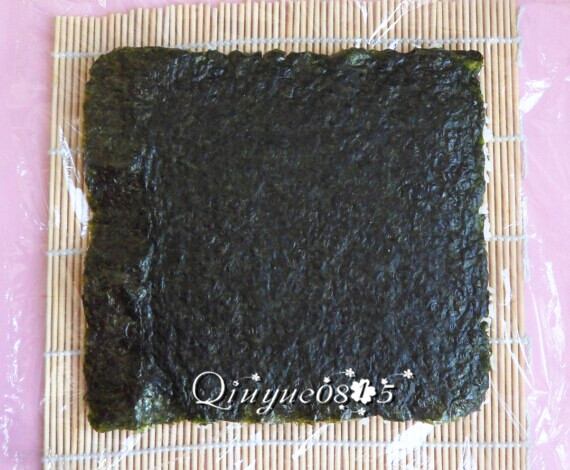 翻转樱花寿司,把米饭和海苔的位置换一下,米饭翻到挨着保鲜膜。如图