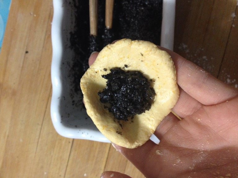 南瓜黑芝麻汤圆,如图取一块面团,将拌好的黑芝麻放里