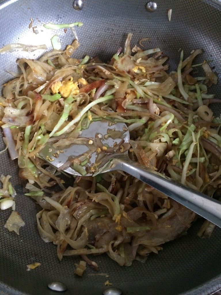 炒饼,如图下入饼丝翻炒,溜少许水,大概十毫升左右,有点儿水汽就可以了,加入少许黑胡椒碎,少许盐和白糖调味