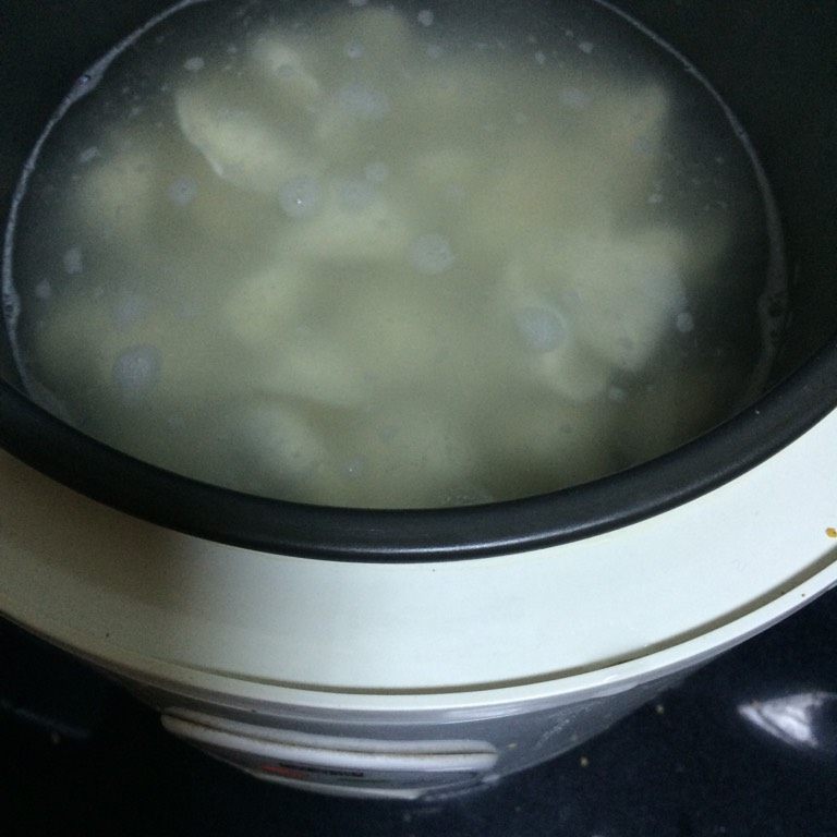 电饭锅煮饺子,如图用勺子推锅底,贴着锅边推,防止饺子粘锅