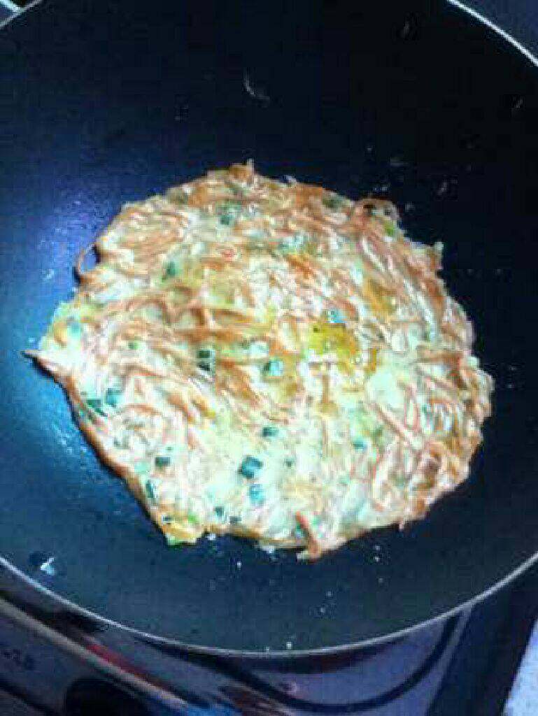 红萝卜鸡蛋煎饼, 上锅加入适量油加热,倒入适量面糊,用锅铲摊平煎至表面凝固