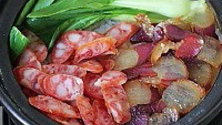 经典广式腊味煲仔饭,十五分钟后，米已煮到八九成熟，将腊肠、腊肉、青菜铺放到米饭表面，火开到最小再煮四分钟，停火后盖着锅盖焖10分钟