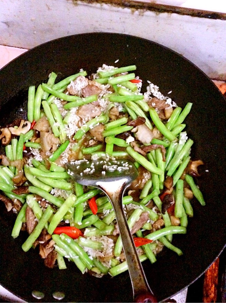 四季豆咸饭,如图把洗好的米放倒入也翻炒下,然后盛锅倒入电饭煲锅