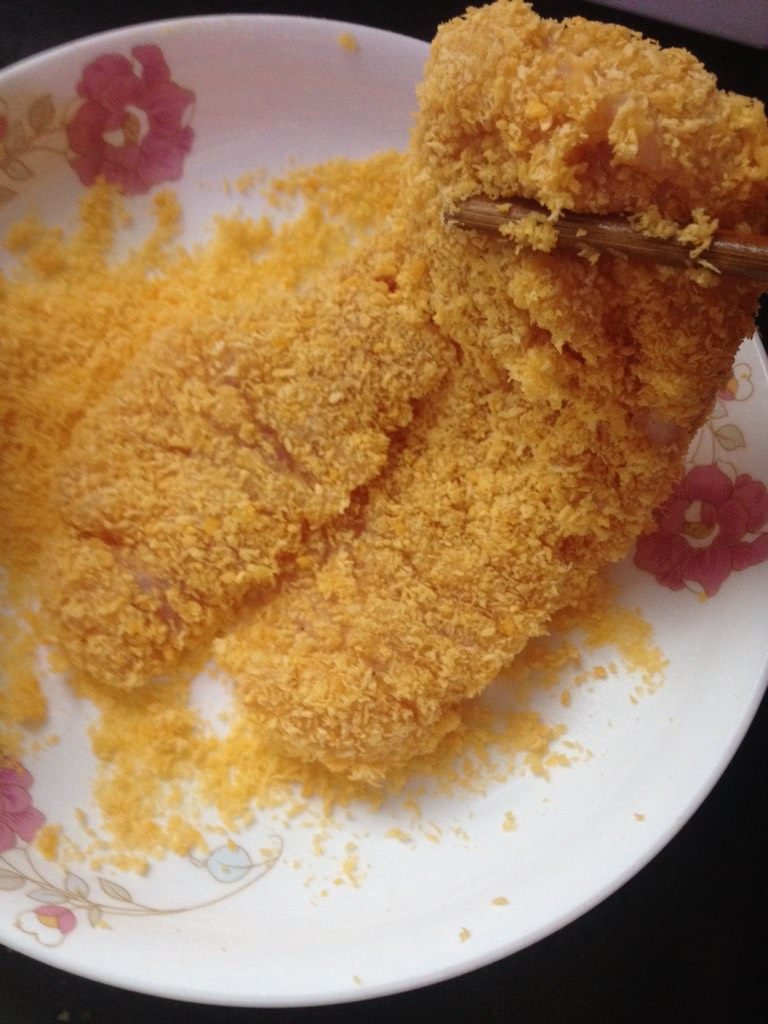 炸鸡排,如图把鸡脯裹上一层鸡蛋液,再滚上一层面包糠