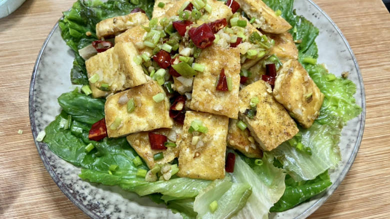 椒盐豆腐,豆腐装盘摆在生菜上,撒上葱末即可上桌享用
