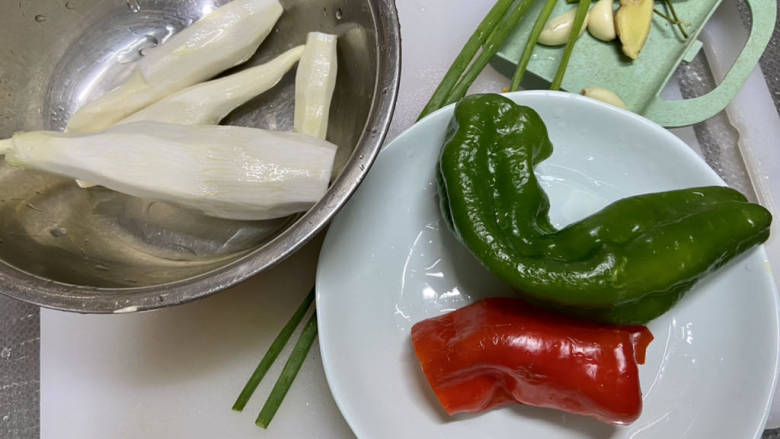 茭白炒鸡蛋,茭白去皮削去根部老皮洗净,青红椒去蒂去籽洗净,小葱择好洗净,蒜剥皮,姜搓洗干净,小米辣洗净