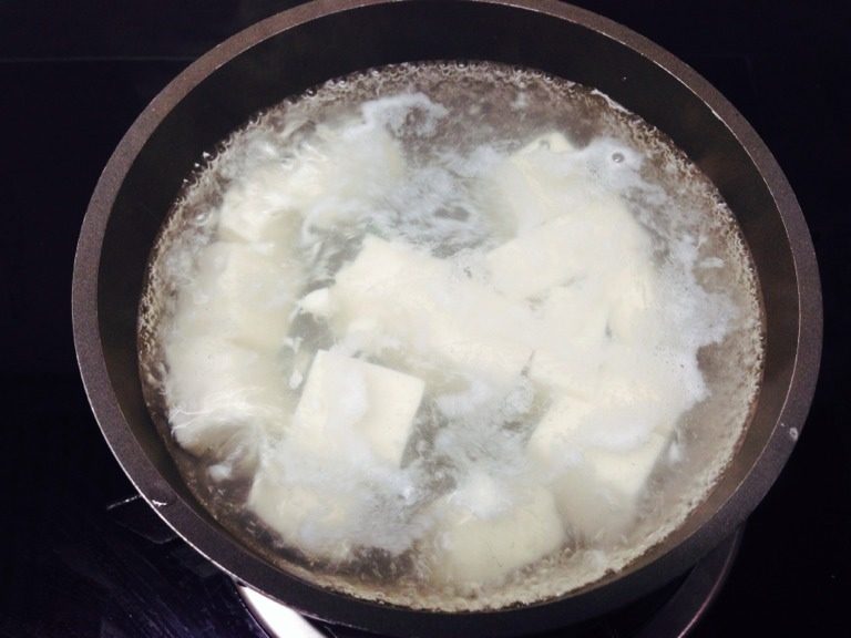 蟹粉豆腐,豆腐切成大约1.5厘米见方小块备用;锅中放入清水煮开,加一勺盐,关火后下豆腐略烫后捞出,过冷水晾凉;