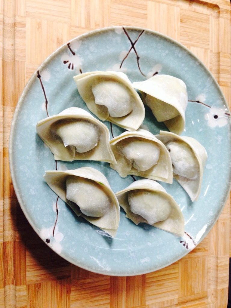 菜肉大馄饨,馄饨皮是买现成的, 在馄饨皮当中放适量的馅。把皮子对折过来,里面的短一些、 再折过来,两边沾点水使其有粘性,拎起馄饨两端捏在一起,按压一下,就包好了。