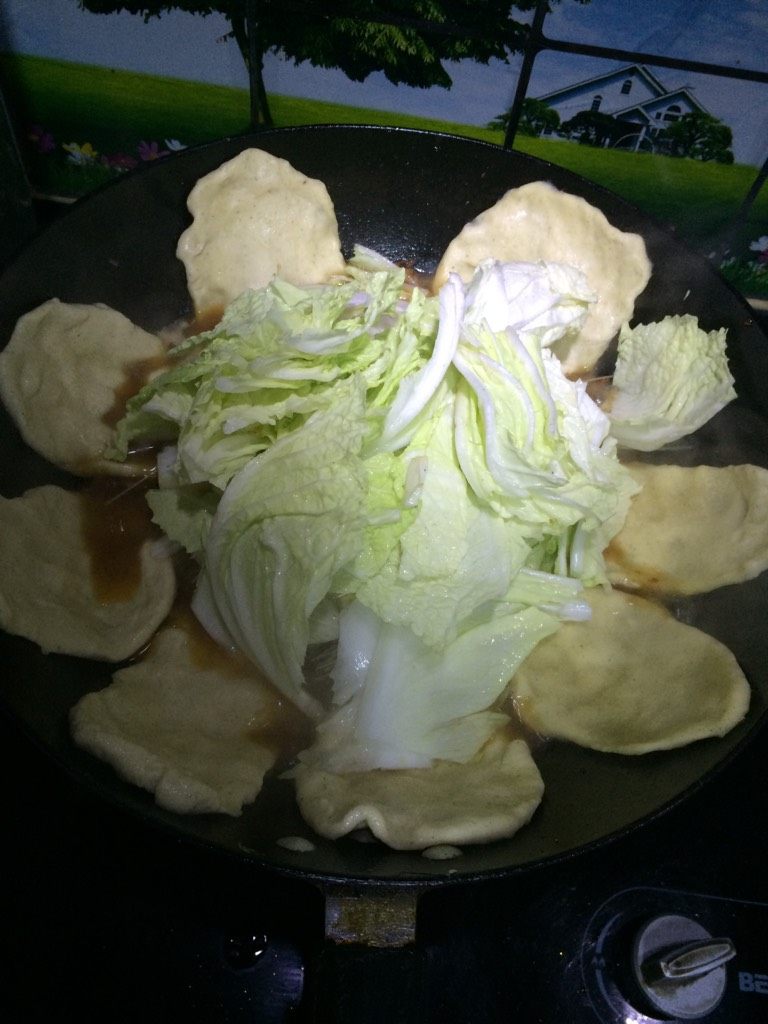 锅贴猪肉白菜炖粉条,如图面饼全部贴完后,再加约两百毫升的开水,下淘洗干净的粉条,中间表面放入白菜块