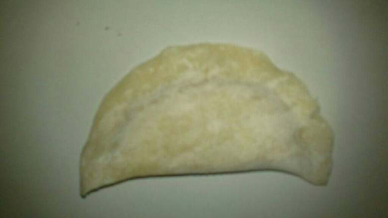 炸油角,用勺子勺一半馅料放在面皮上后,对半折,用手粘紧,如图示