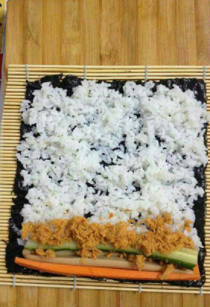 家常寿司卷,铺寿司帘，摊开紫菜，先将饭铺平，再将黄瓜条、胡萝卜条、火腿条、<a style='color:red;display:inline-block;' href='/shicai/ 432'>肉松</a>放上
