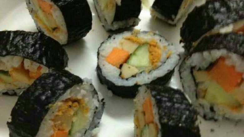 家常寿司卷,用手推动帘子，顺势用竹帘将紫菜卷起，卷起时尽量压实压紧，卷成形后，切段即可