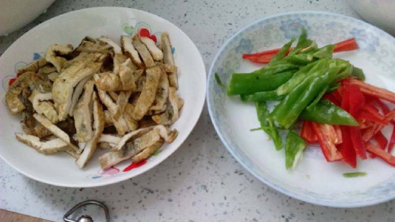 辣椒炒臭干（臭豆腐）,将材料切丝，蒜切片。