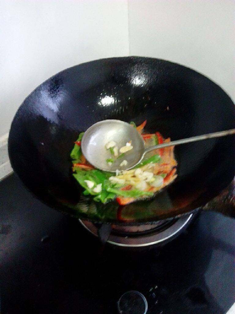辣椒炒臭干（臭豆腐）,锅油加热，下青红椒煸炒，再下入蒜片。