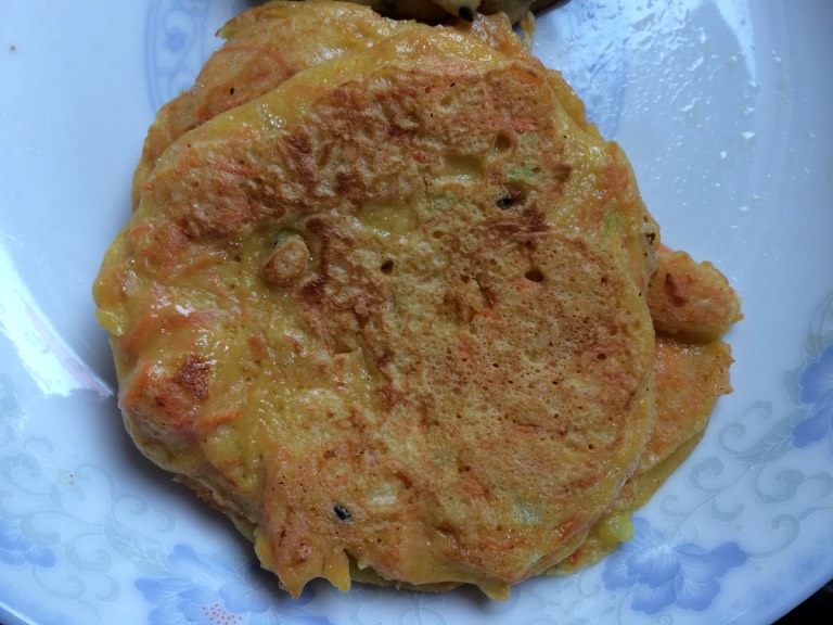 胡萝卜煎饼,如图感觉饼底部凝固可以晃动平底锅,饼可以移动发出沙沙的响声即可翻面煎制另外一面,两面煎制金黄即可出锅