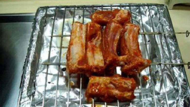 叉烧排骨,排骨腌好后,把排骨用两根钢钎串起来放在烤架上。
