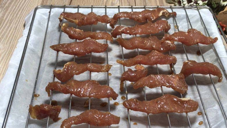 烤里脊肉,烤网放在铺好油纸的烤盘上,再摆上腌制好的里脊肉