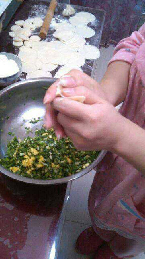 韭菜鸡蛋饺子,挖一勺馅料放在面饼中间。将面饼中间先捏住。两个手其它手指拖住饺子，拇指分别从两边往中间挤饺子就成了。（如果不会挤直接将口捏紧了不漏馅就可以）。