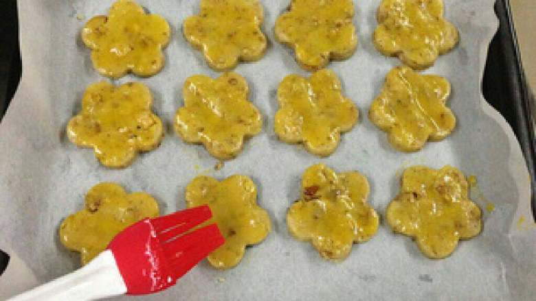 【宫廷核桃酥】, 烤盘放一张油纸，把核桃酥放入。表面上刷一层蛋液。
