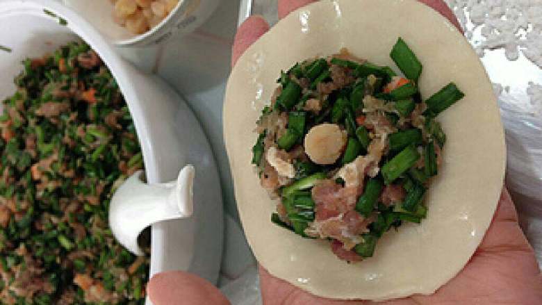 【私房韭菜饺子】,所有材料准备好:包皮、馅料等。取一张饺皮,放入馅料,皮边抹上清水。