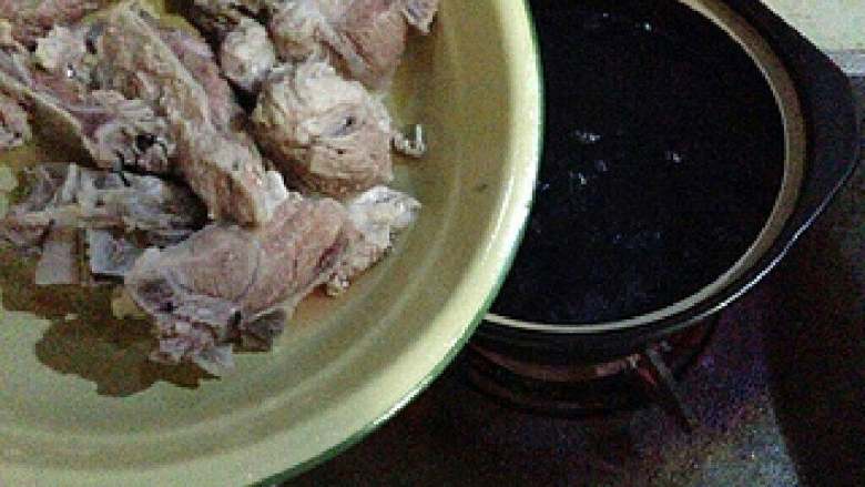 【猪骨黑豆汤】,砂锅中煮开水,加入猪骨。 煮开再次抹掉浮沫。