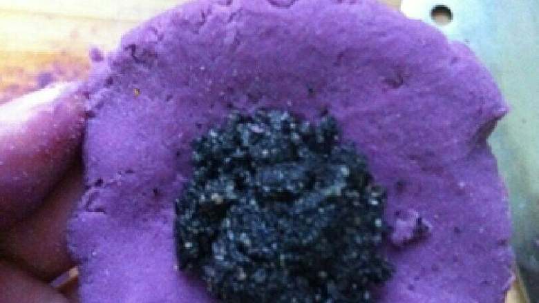 紫薯芝麻球~情人节礼物,把紫薯面团压扁,摊平放手心,放入黑芝麻馅,包起来搓圆。