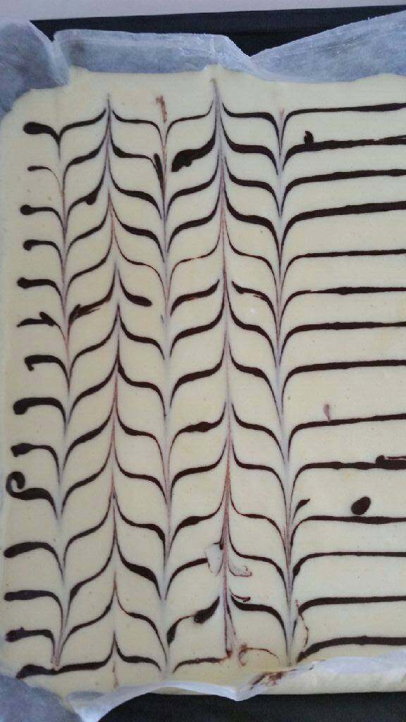 千叶纹蛋糕卷,挤出可可蛋糕糊,在蛋糕糊上画横线,再用竹签第一行正方向直划,第二行反方向直划的方式划出花纹