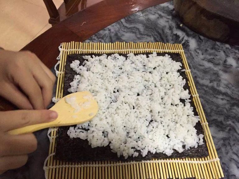 最简寿司,把<a style='color:red;display:inline-block;' href='/shicai/ 279'>海苔</a>放在竹帘上，放上一层米饭，再把材料排列在上，就可以卷了