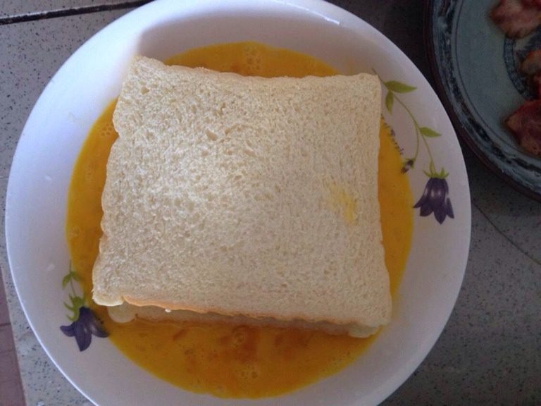 培根芝士煎吐司,如图把面包放<a style='color:red;display:inline-block;' href='/shicai/ 9'>鸡蛋</a>里粘一下<a style='color:red;display:inline-block;' href='/shicai/ 9'>鸡蛋</a>再放锅里煎