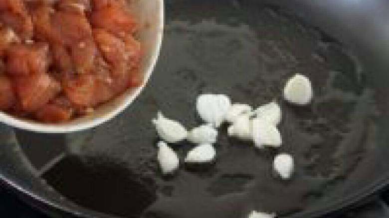 菠萝鸡丁,起油锅,油热先下蒜瓣,接下来就下拌好味的鸡丁。