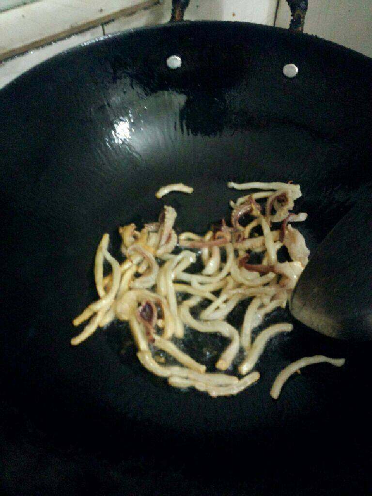 什锦粥,锅倒入油烧热先把切好的干鱿鱼丝放入炒