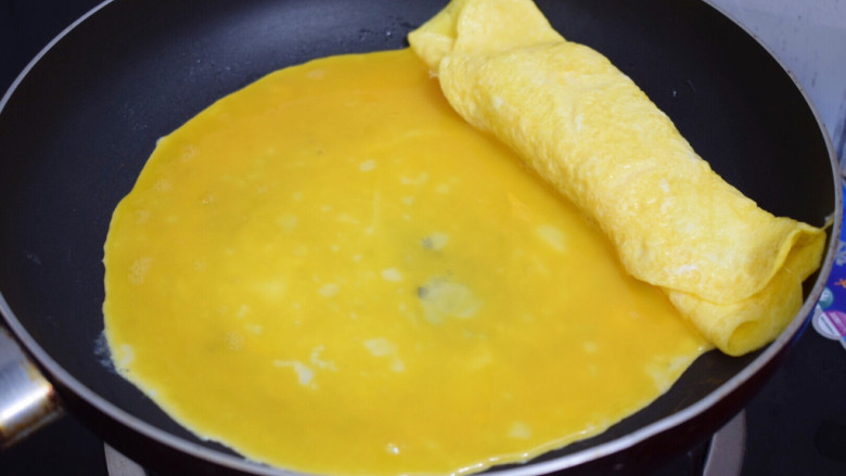 秋葵煎蛋,接着再倒入1/3的蛋液铺满锅底,等底部凝固表面还没凝固时再卷回来