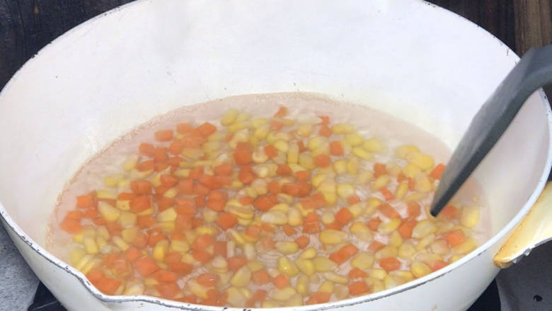 玉米虾仁蛋炒饭,起锅烧开水,放入红萝卜和<a style='color:red;display:inline-block;' href='/shicai/ 4802'>玉米粒</a>,拌匀,煮至断生,捞出备用