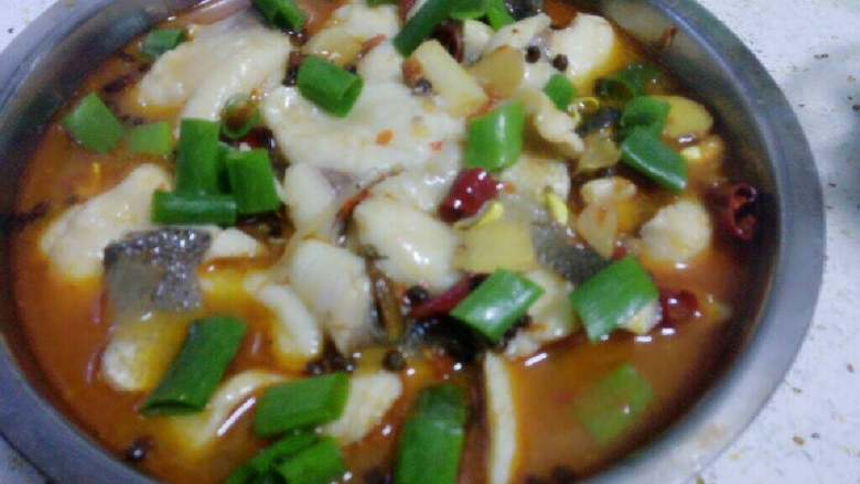 水煮鱼,加入适量盐味和鸡精后,出锅装入盛黄豆芽的盆里。洒上大葱叶段。