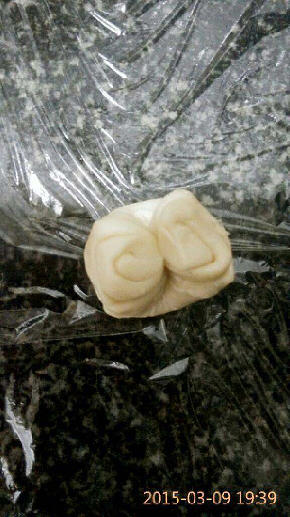 椰蓉开口酥,取一份酥皮，用手指中间压下将两头往中间推，用擀面杖或手将酥皮擀成中间厚四面薄的面皮，要是没有硅胶垫用保鲜膜铺在案板上防粘