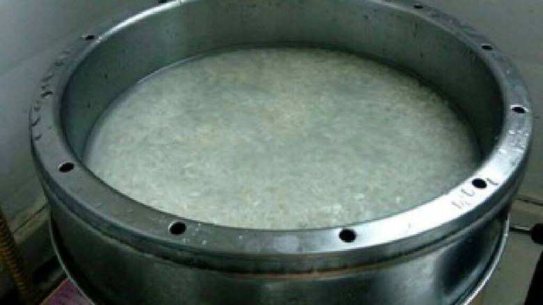 香菇滑鸡蒸饭,洗米后将米加入蒸笼,加入适量的浸泡香菇的温开水。蒸锅水烧开后,放蒸笼。