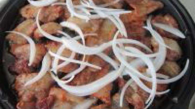 香煎五花肉,翻面,撒上洋葱丝继续煎