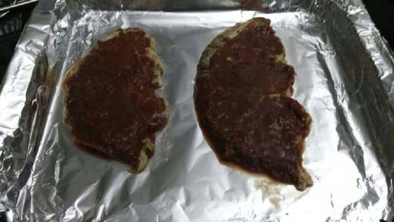 烤牛扒,烤盘先铺上一层锡箔纸,再将预先腌制好的牛扒摆好。