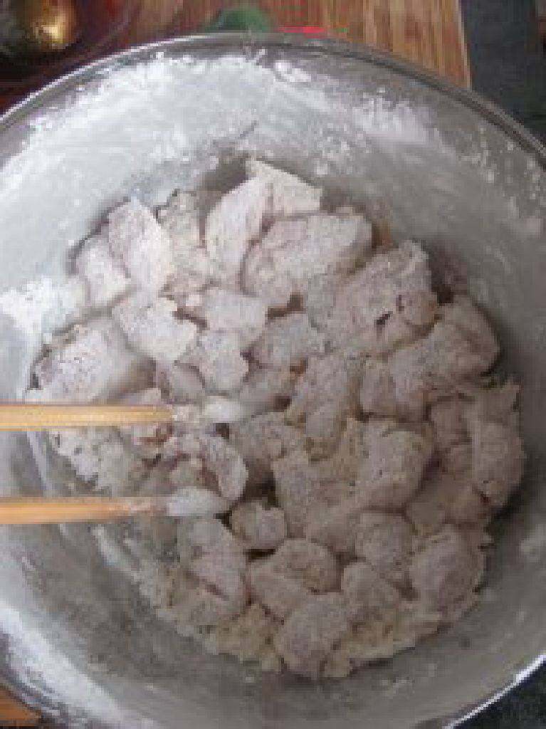 菠萝咕噜肉,肉块倒入淀粉中沾裹均匀。让肉块均匀的裹满淀粉。