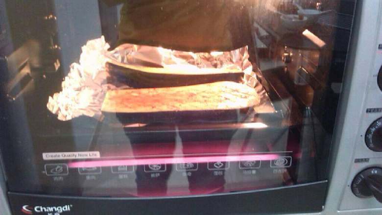 烤茄子,烤箱上下150°预热后放入烤盘,烤15分钟,中间刷油两次(并且先后放上萝卜干跟蒜蓉,最后洒上葱花)。