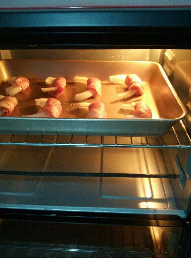 培根卷洋葱,烤箱200度预热15分钟，把卷好的洋葱摆放在烤盘上面，烤20分钟